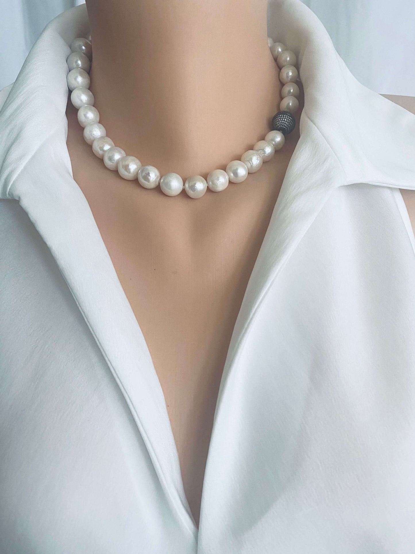 White Edison pearl necklace with gunmetal pavé magnetic clasp worn on a mannequin with a white blouse.