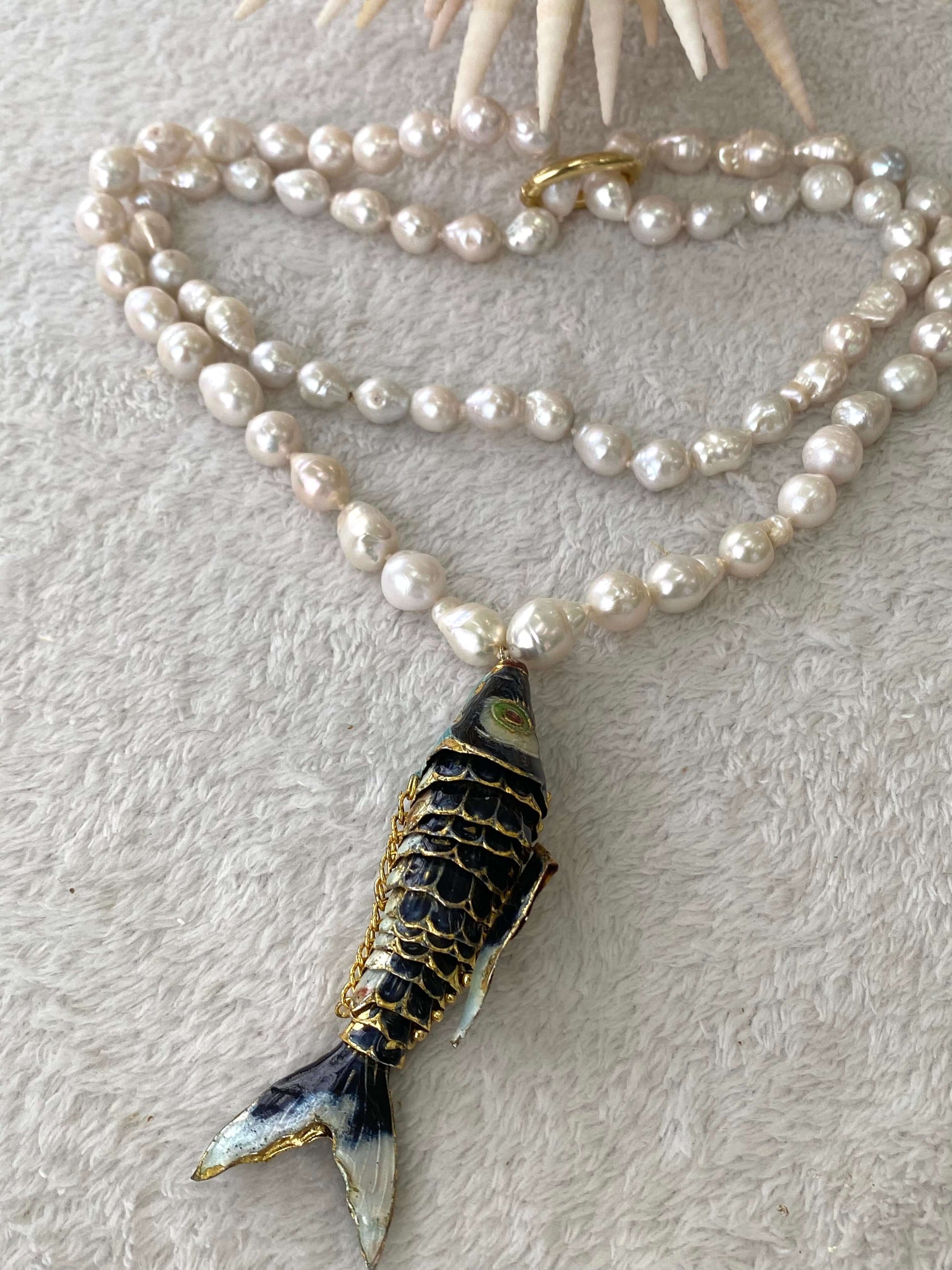 Fish pendant pearl necklace featuring black cloisonné fish and white baroque pearls.