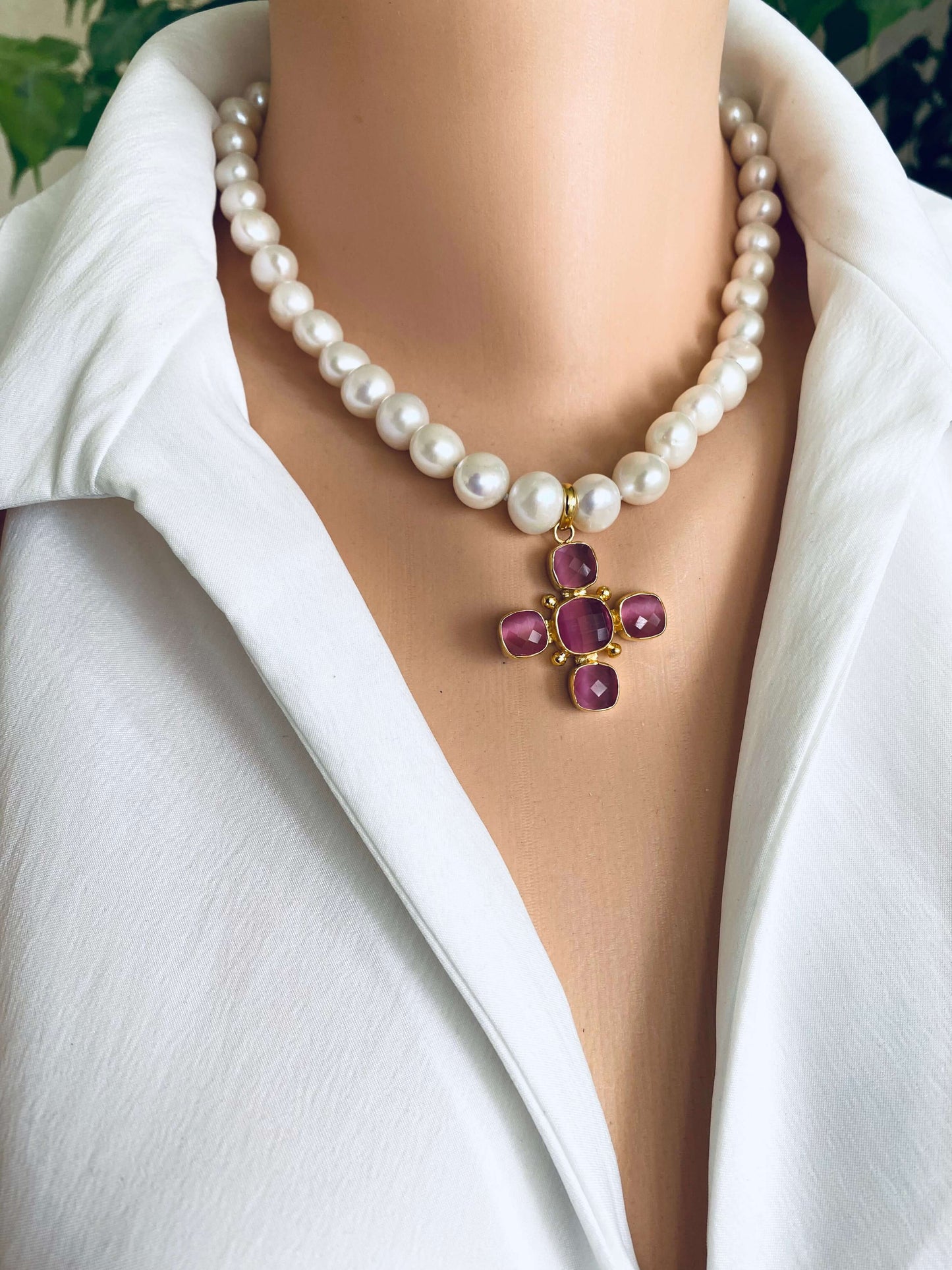White potato pearl necklace with cross pendant adorned with pink gemstones, elegantly shown on a mannequin.