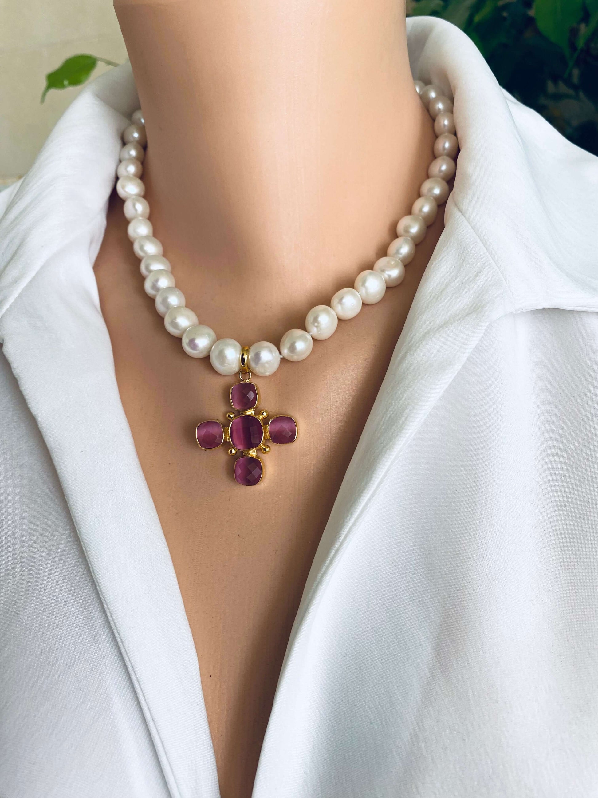 White potato pearl necklace with cross pendant featuring pink accents, elegantly displayed on a mannequin neck.