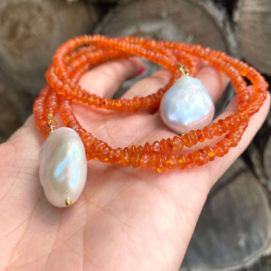 Carnelian lariat necklace with two baroque pearls showcasing vibrant orange beads and organic textures.