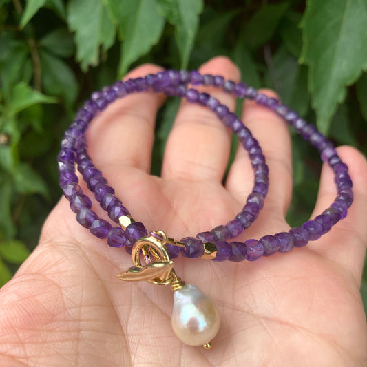 Amethyst toggle necklace with baroque pearl charm held in hand, showcasing its rich purple hue and elegance.