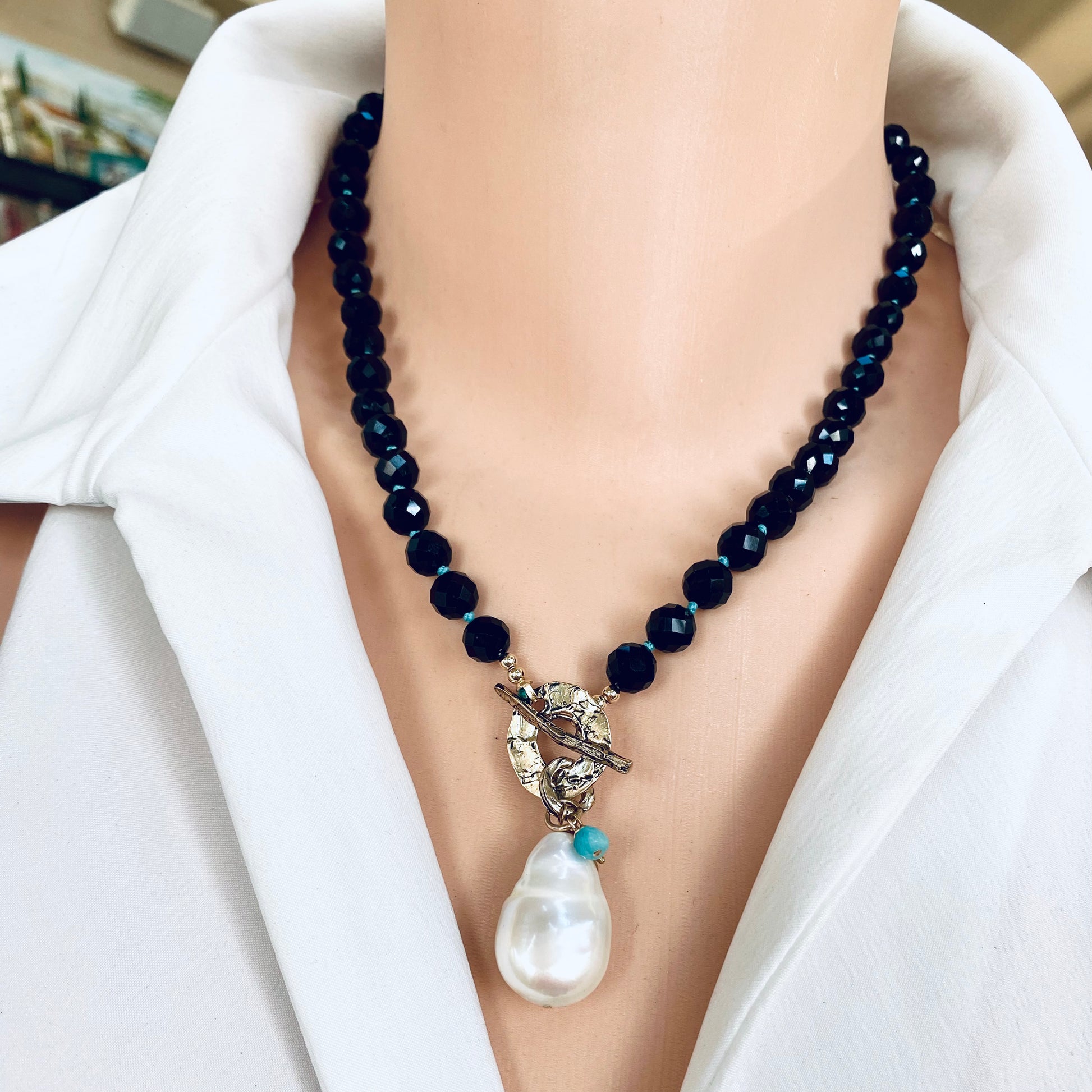 Black tourmaline baroque pearl toggle necklace worn on model showing pearl pendant and charms