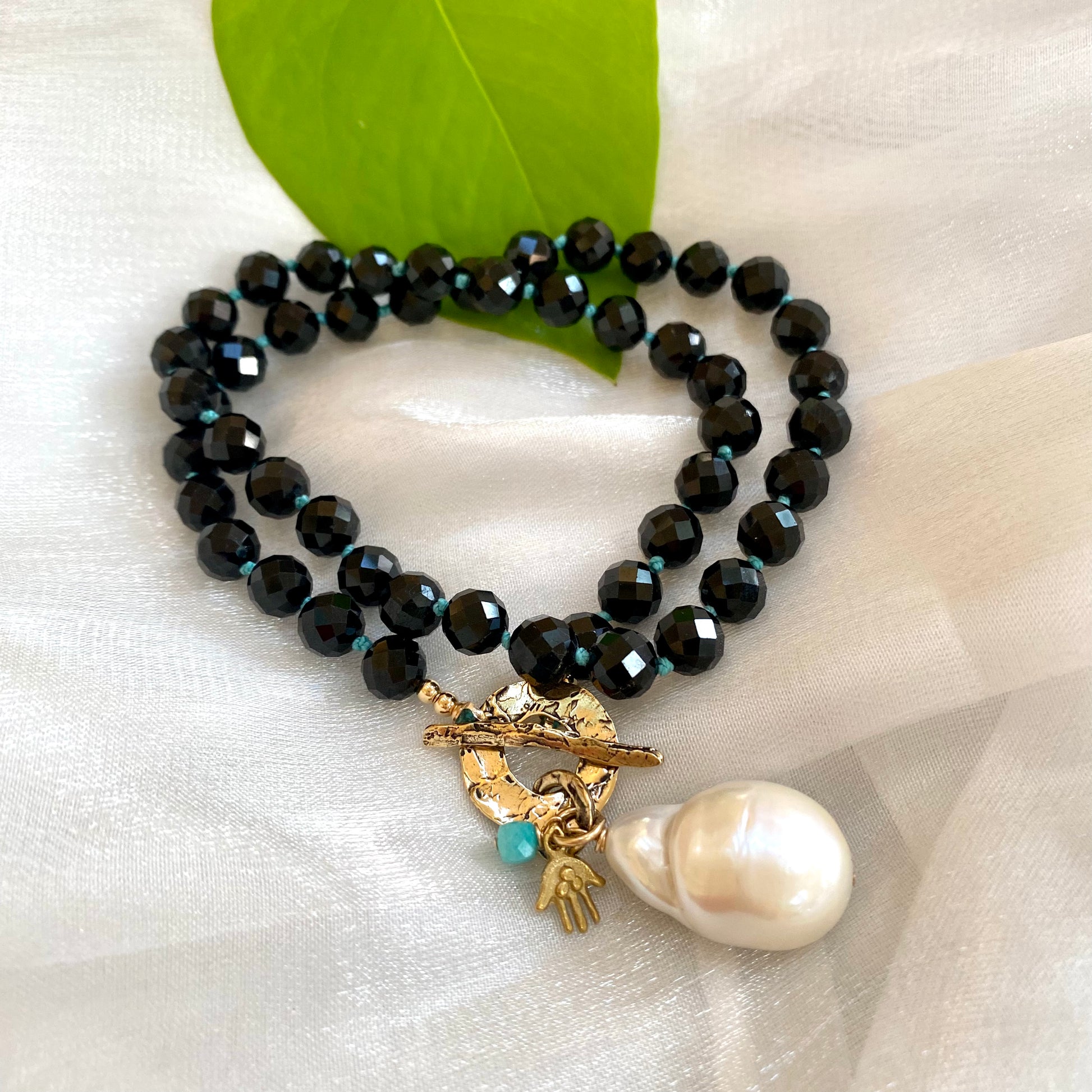 Black tourmaline baroque pearl toggle necklace displayed flat highlighting toggle clasp and pearl