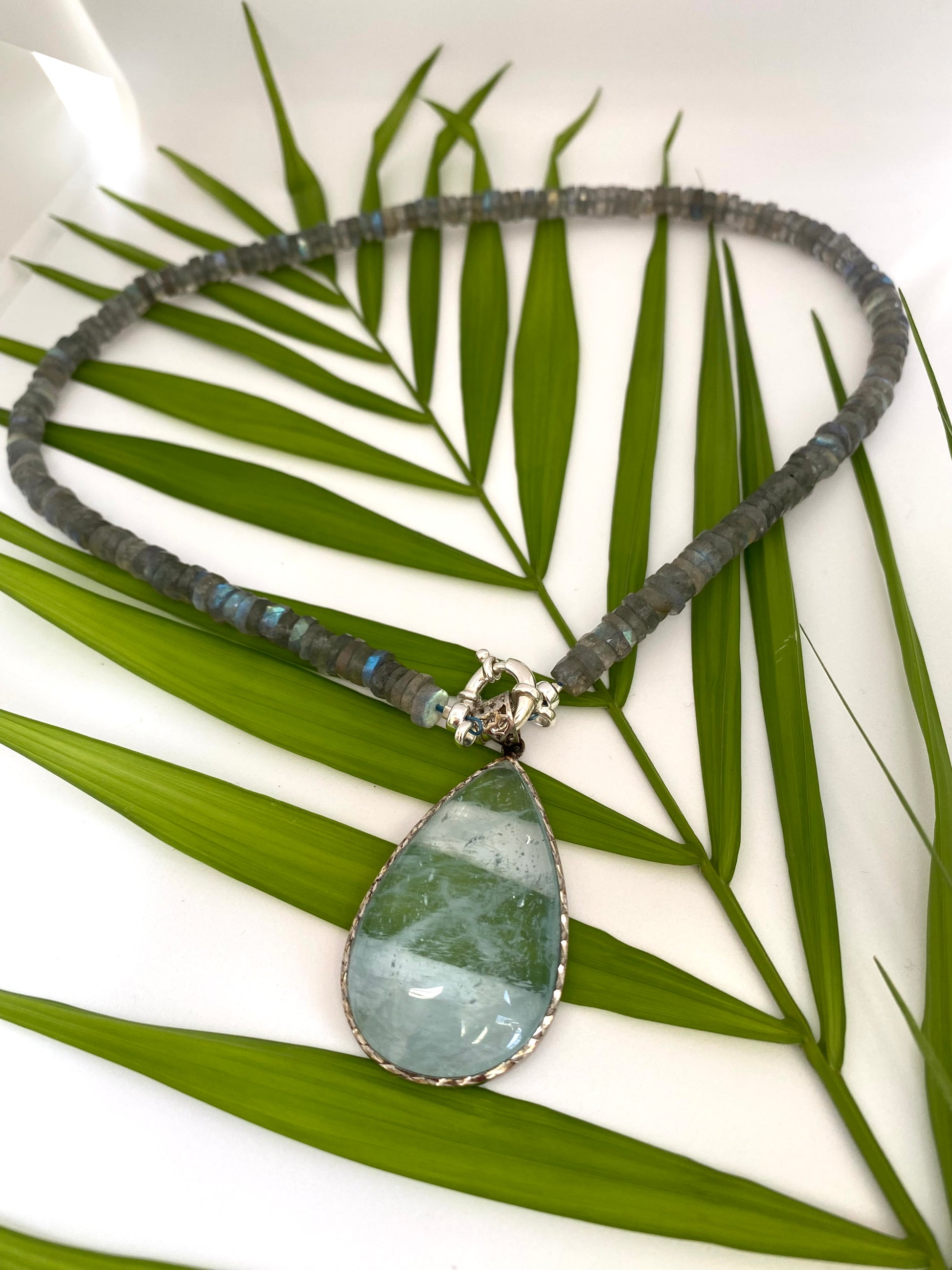 LABRADORITE Necklace with a green teardrop pendant on a leafy background
