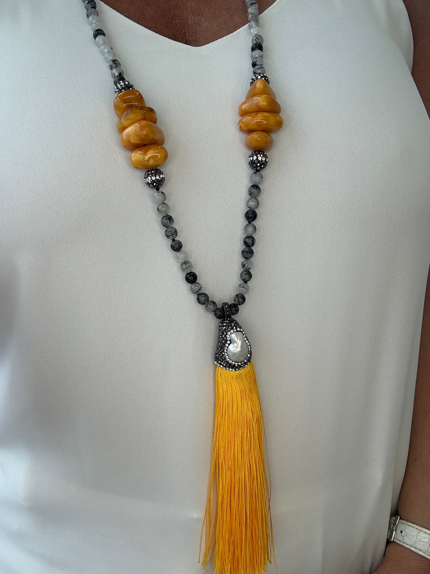 Necklace with yellow tassel and beads on a white surface