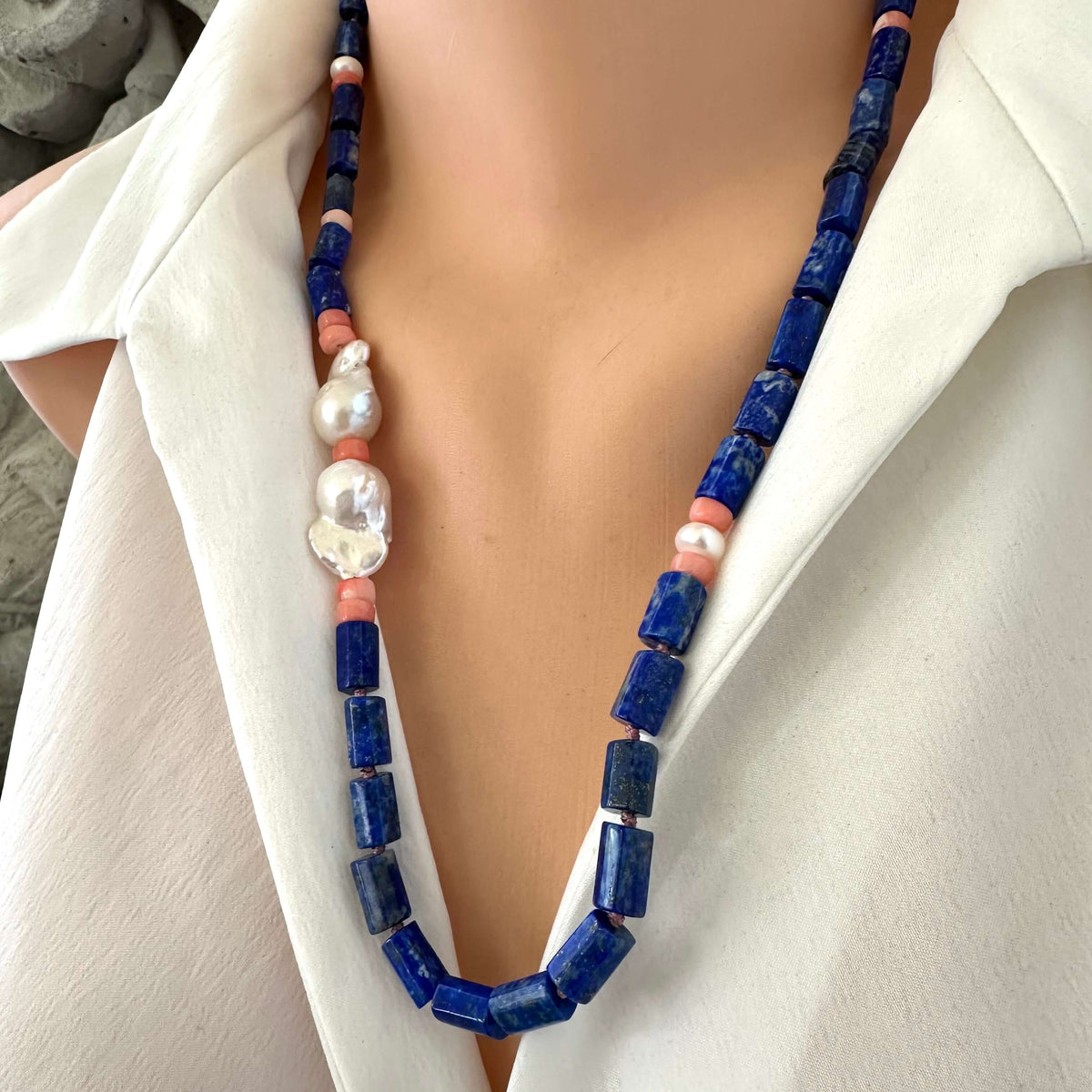 Lapis lazuli necklace with pink coral and baroque pearls, showcasing deep blue beads and elegant accents on a mannequin.