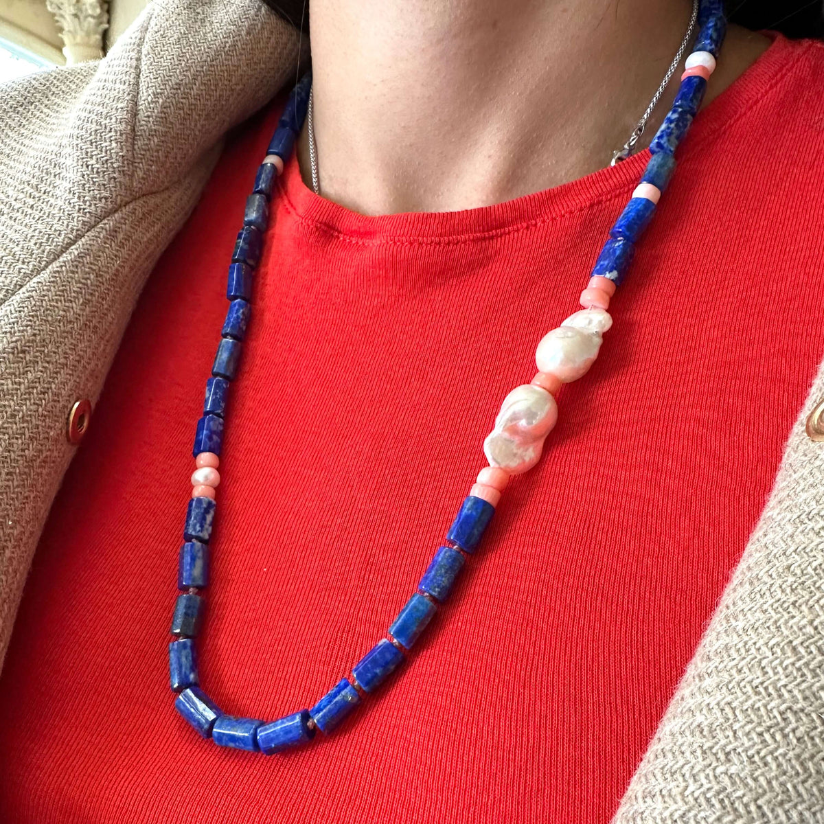 Lapis lazuli necklace with pink coral and baroque pearls showcased on a model's neck, featuring vibrant colors and textures.