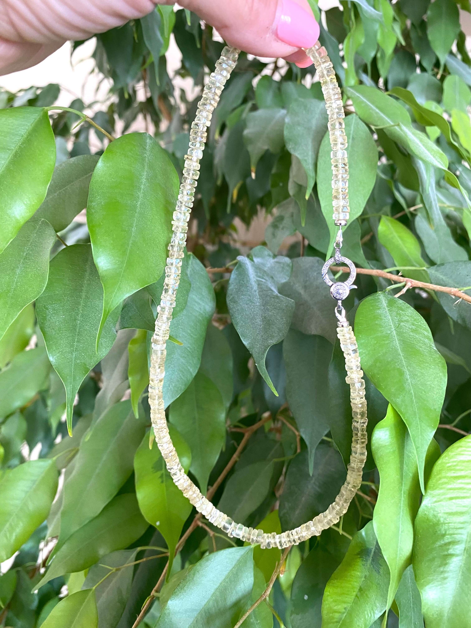 Lemon quartz beaded necklace with oxidized silver pavé clasp displayed against lush green leaves.