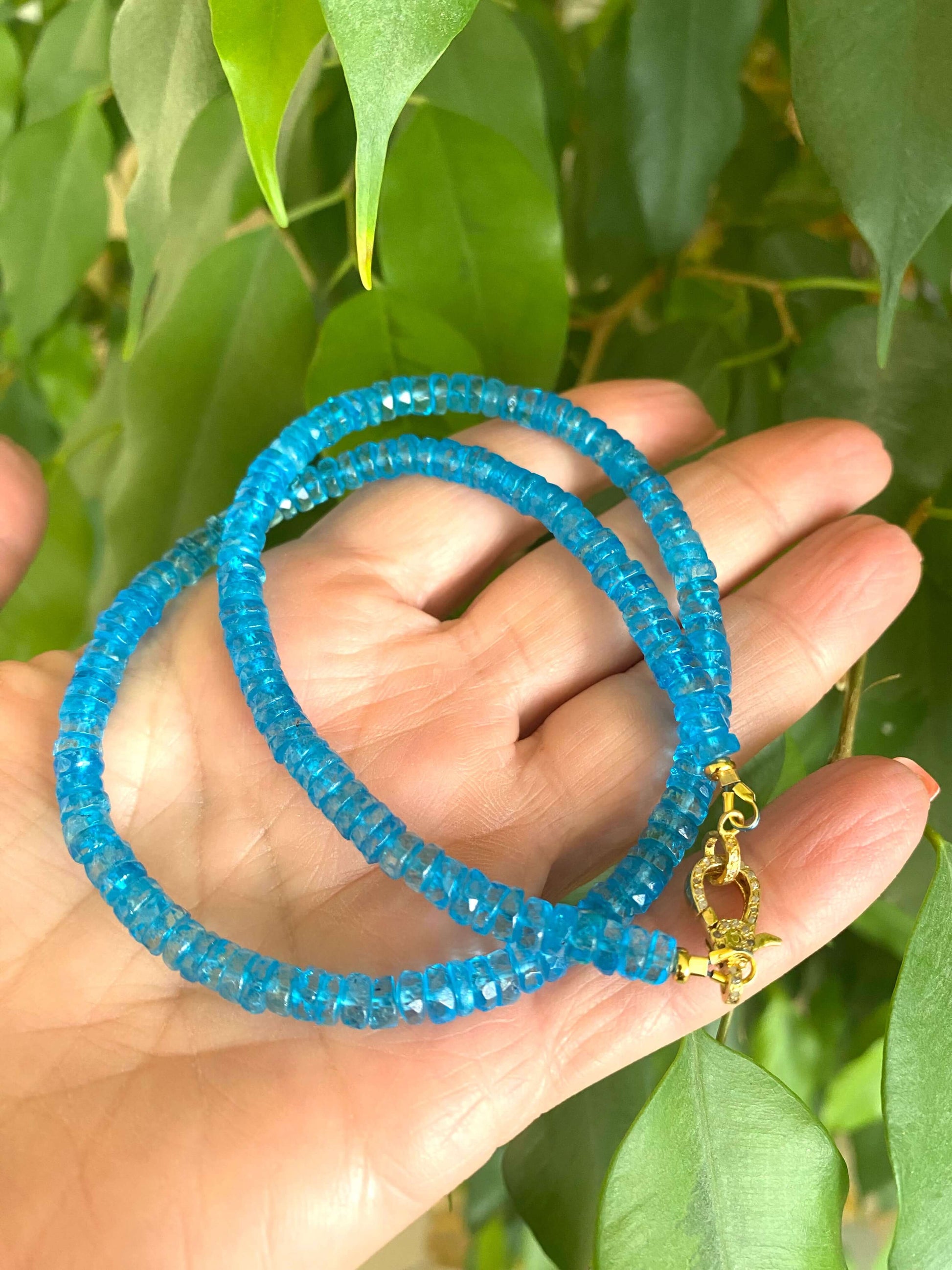 Blue topaz beaded necklace with gold vermeil pavé clasp held in hand, showcasing vibrant color and craftsmanship.