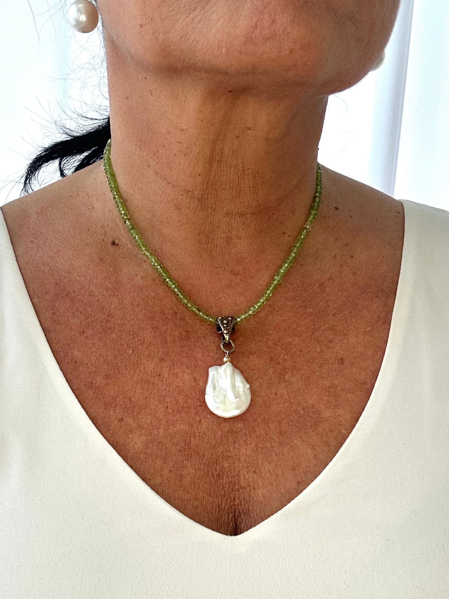 Necklace with a shell pendant worn by a person against a white background