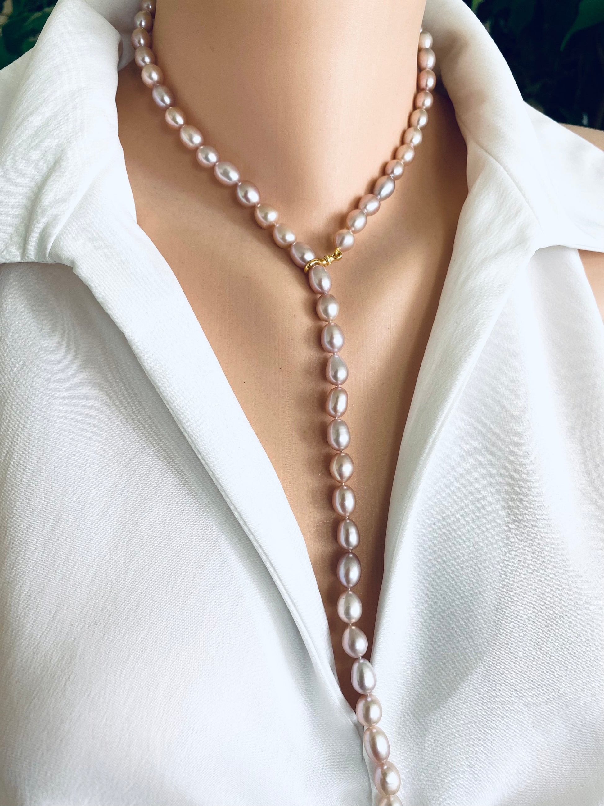 Pearl necklace worn by a person in a white shirt