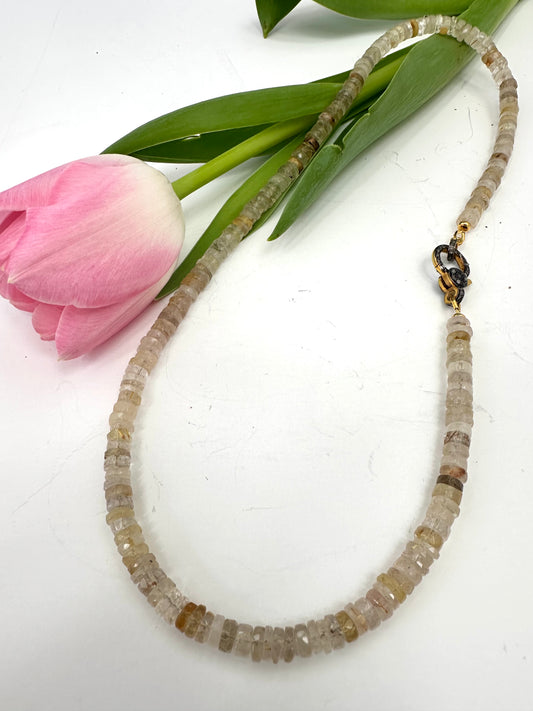 Necklace with beaded design on a white background with a pink tulip and green leaves.