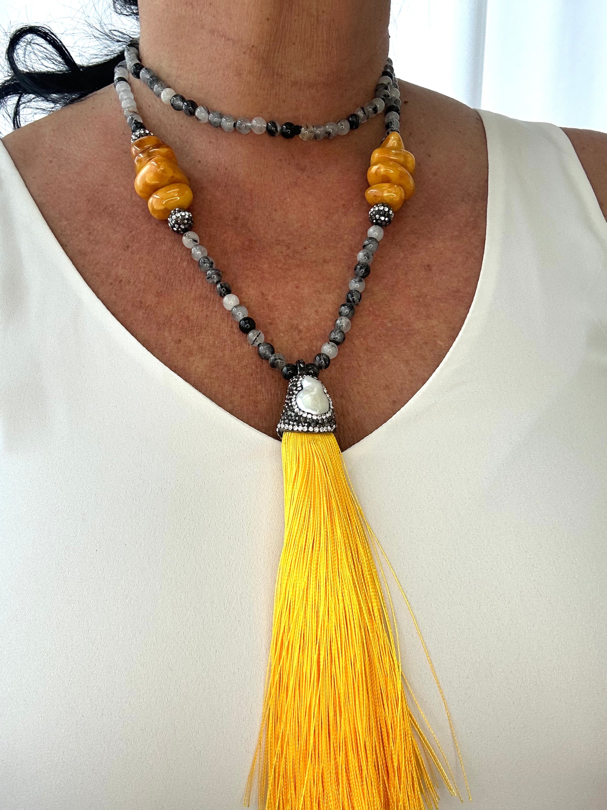 Necklace with yellow tassel and beads on a white background