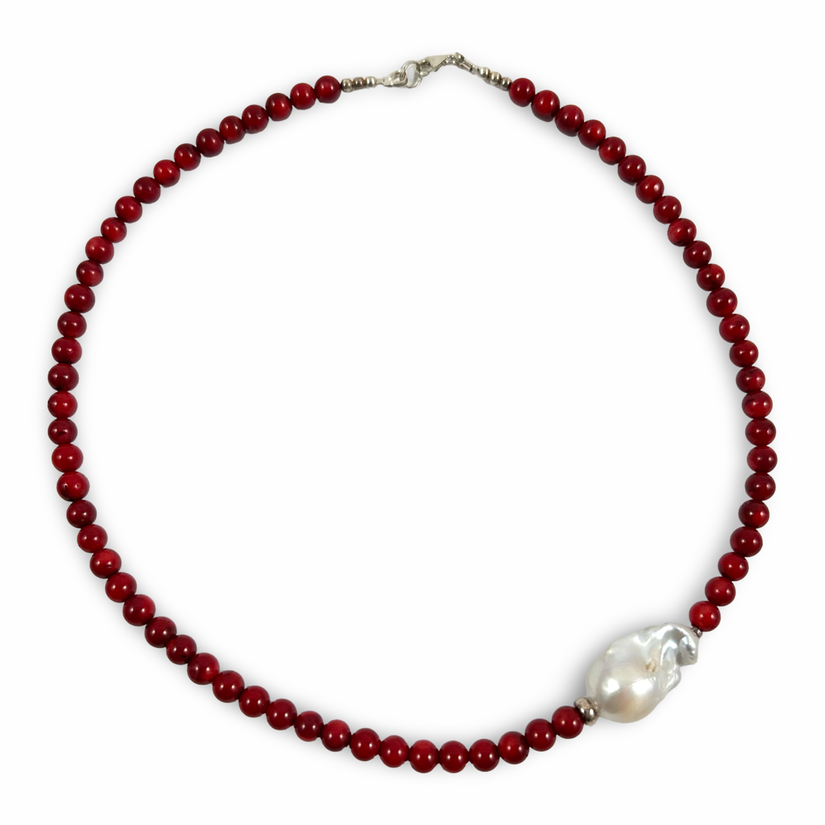 A beaded necklace featuring deep red round beads and a large, irregular white baroque pearl set in silver-toned metal, displayed on a clean white background.