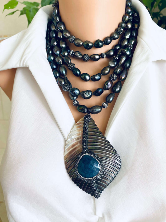 Necklace with black beads and a large pendant on a white shirt