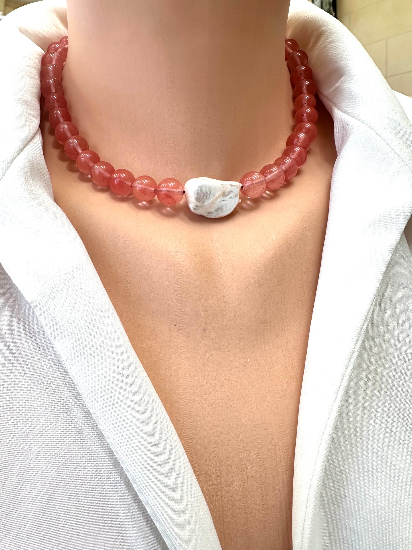 Necklace with pink beads and a white stone on a white background