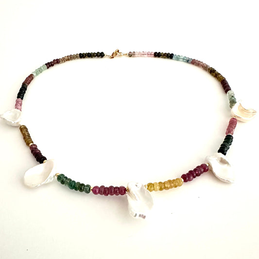 A beaded necklace featuring small multicolored gemstone beads and several white shell charms, displayed on a plain white background.