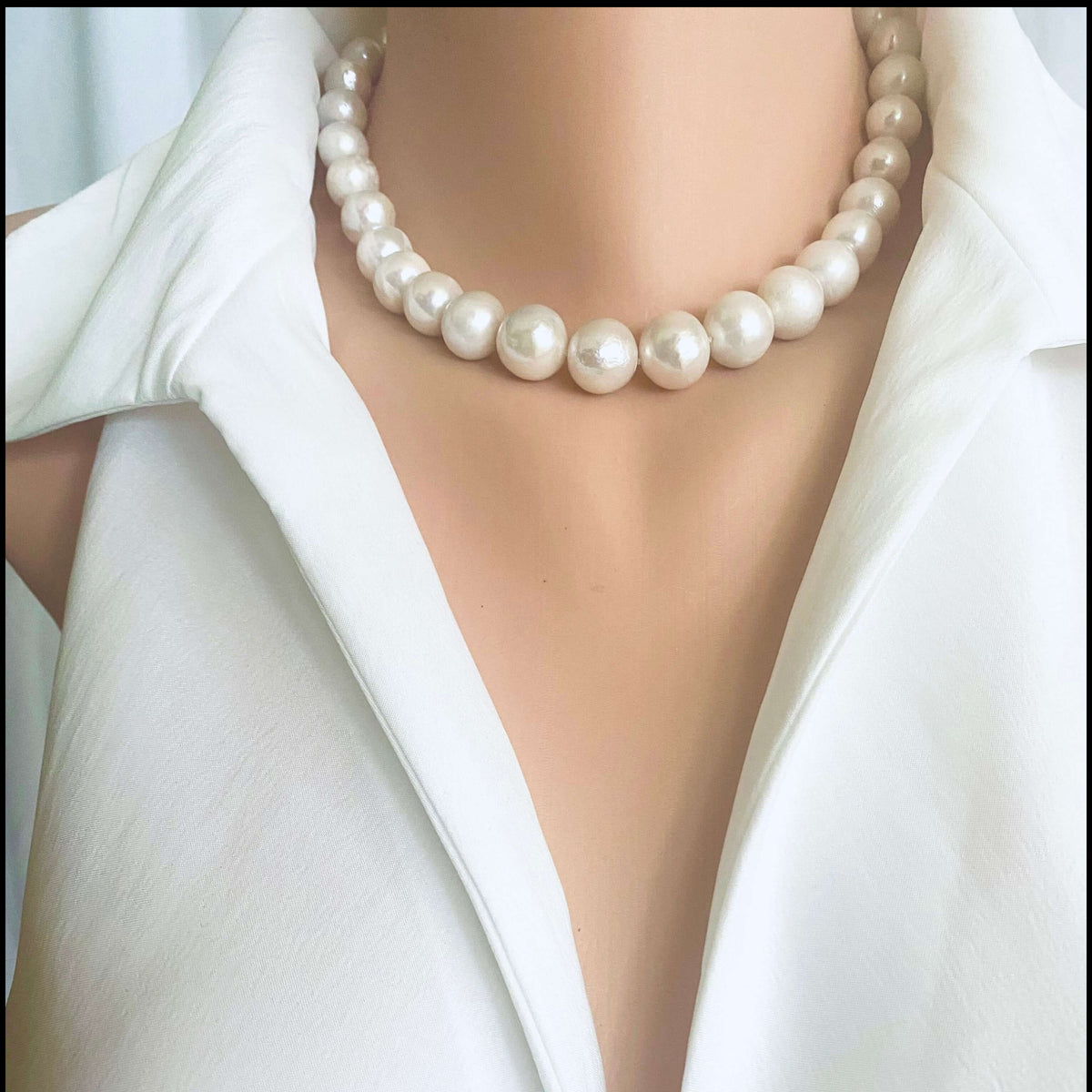 White Edison pearl necklace with large luminous pearls showcased on a mannequin wearing a white collared shirt.