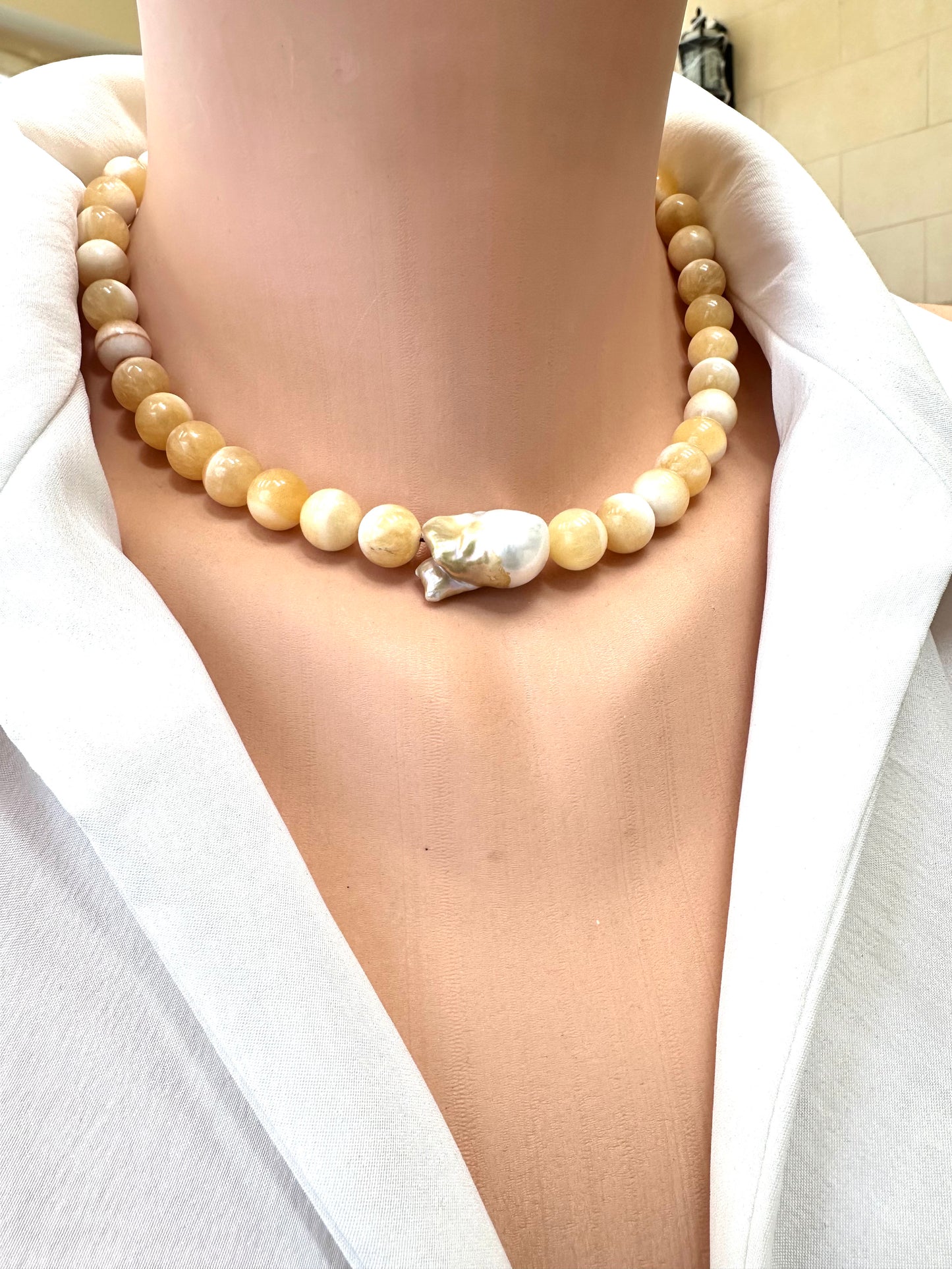 Pearl necklace worn by a person in a white outfit