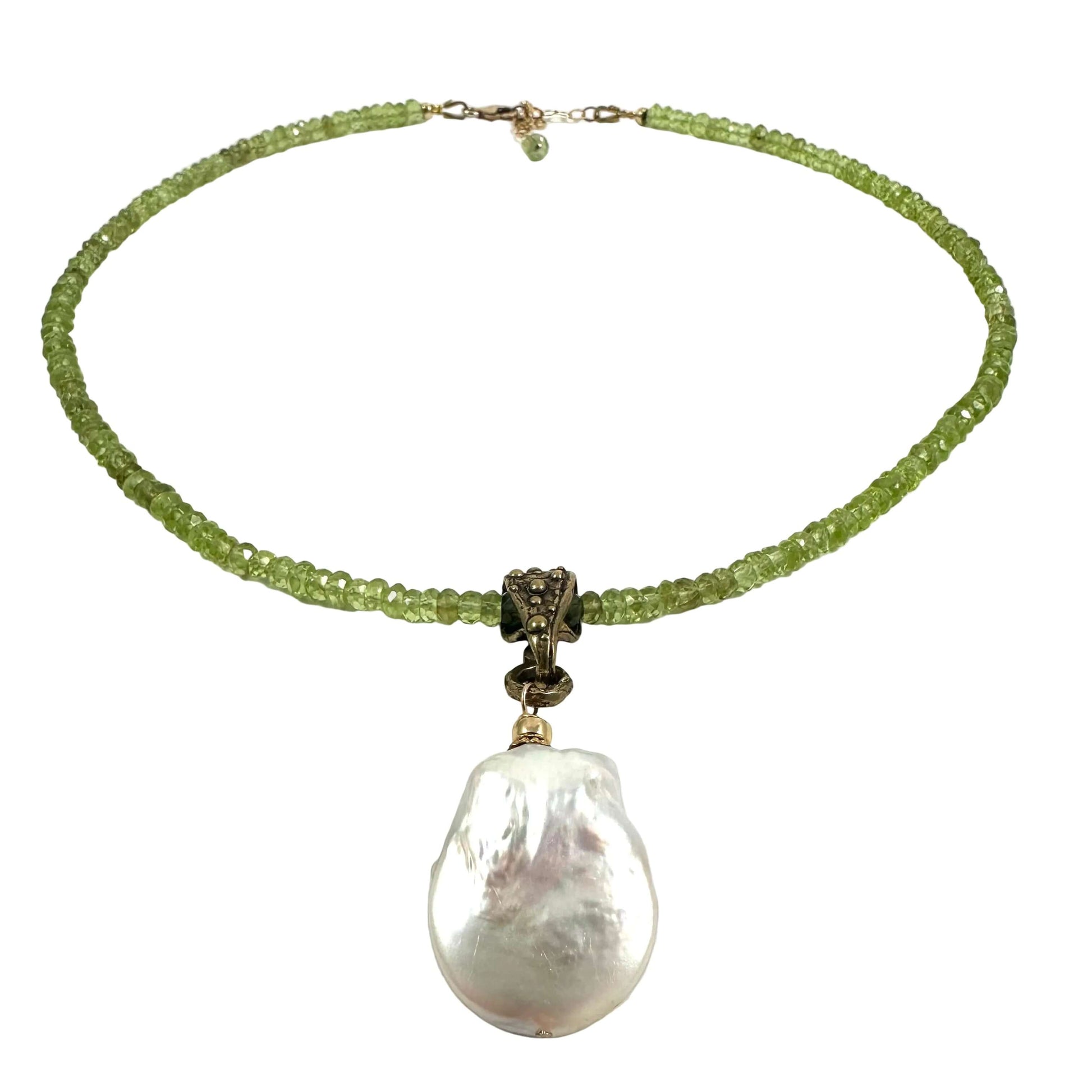 A beaded necklace featuring a strand of light green faceted beads, a bronze-toned central connector, and a large, irregular white baroque pearl pendant, displayed on a clean white background.