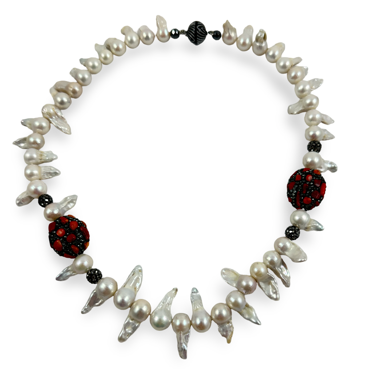 A statement necklace featuring irregular white freshwater pearls, sharp silver-gray glass shards, and two large red and black beaded medallions, displayed on a clean white background.