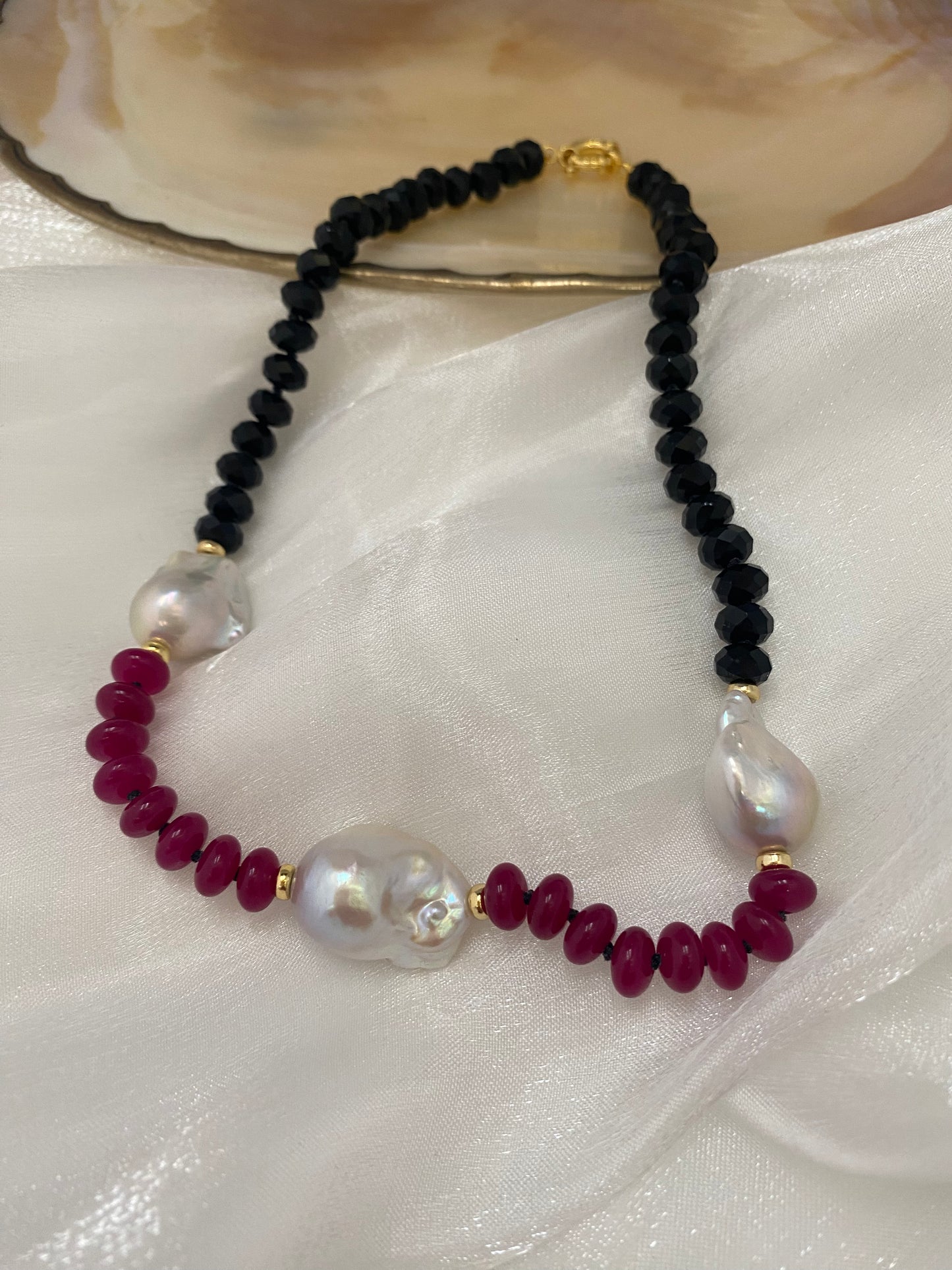 Necklace with black, red, and white beads on a white fabric background
