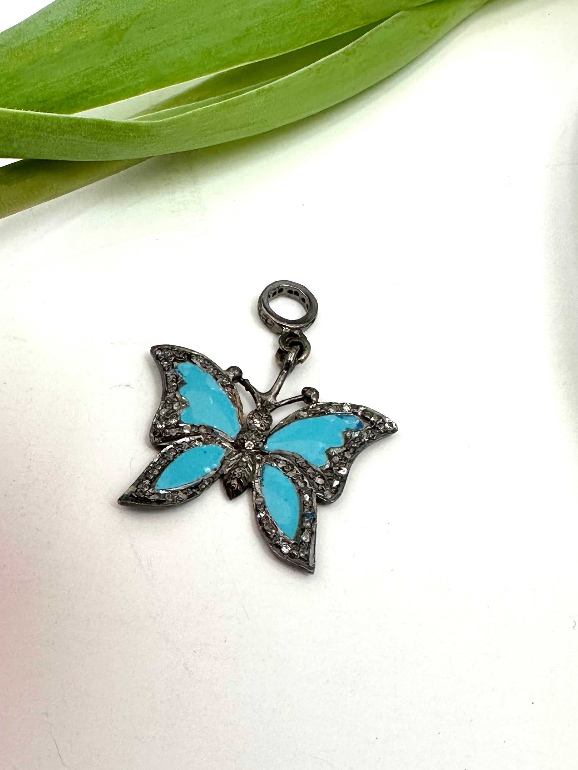 Butterfly-shaped pendant with turquoise wings on a white background