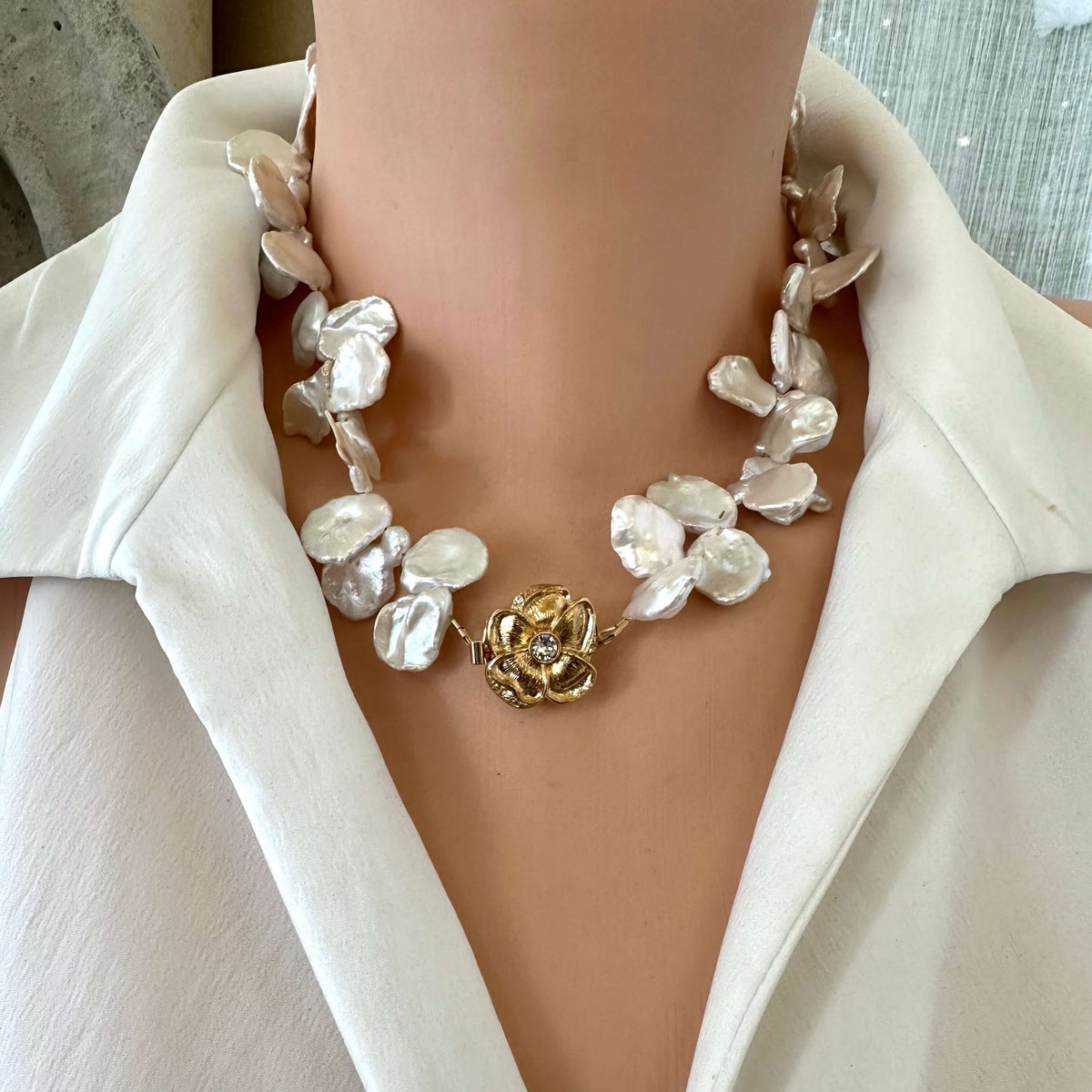Front close-up of white keshi pearl necklace with flower clasp on mannequin showing petal pearls and gold clasp