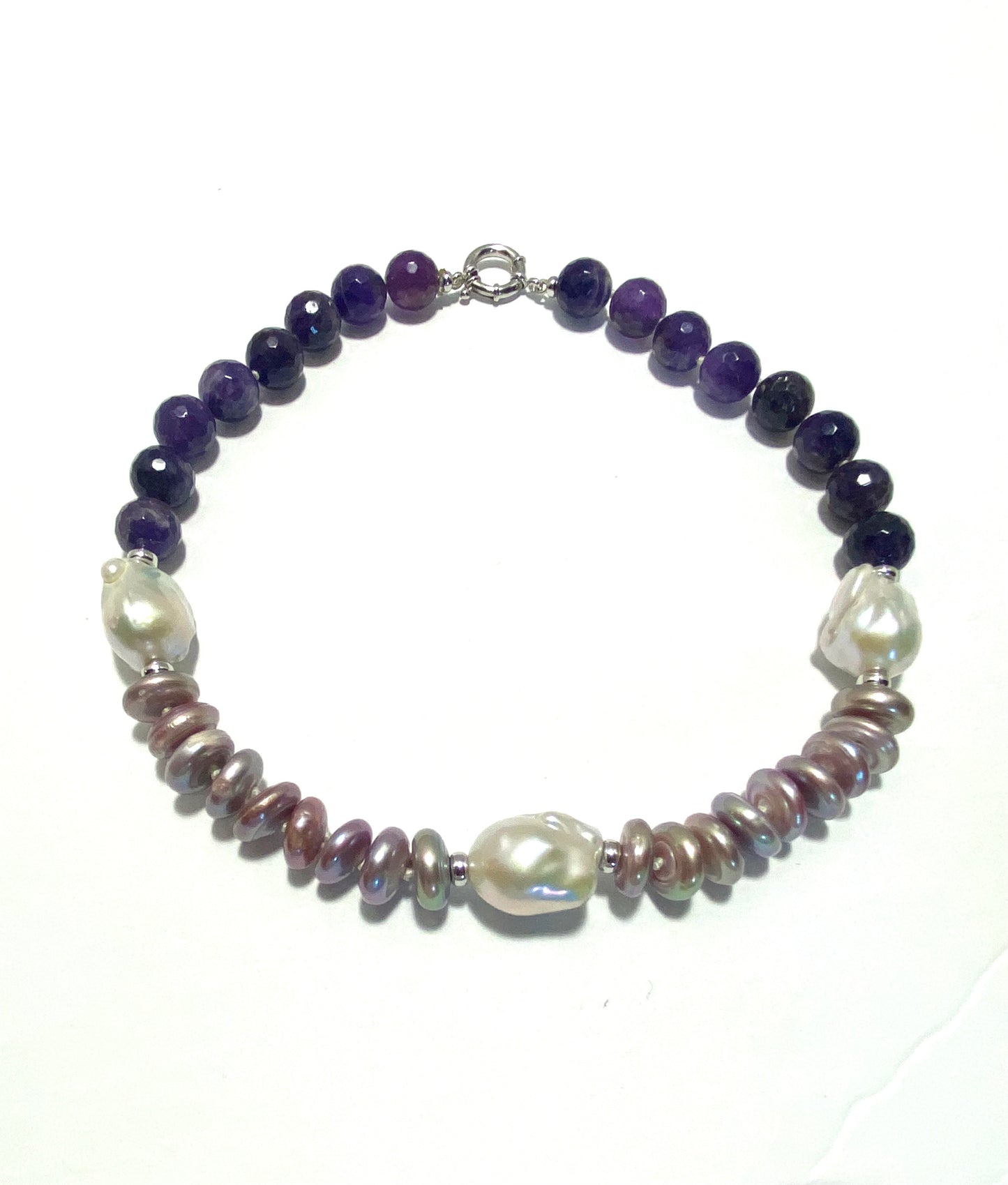 A beaded necklace featuring dark purple AMETHYST, large white baroque pearls on the other, and small metallic PINK PEARLS in the middle, displayed on a white background.