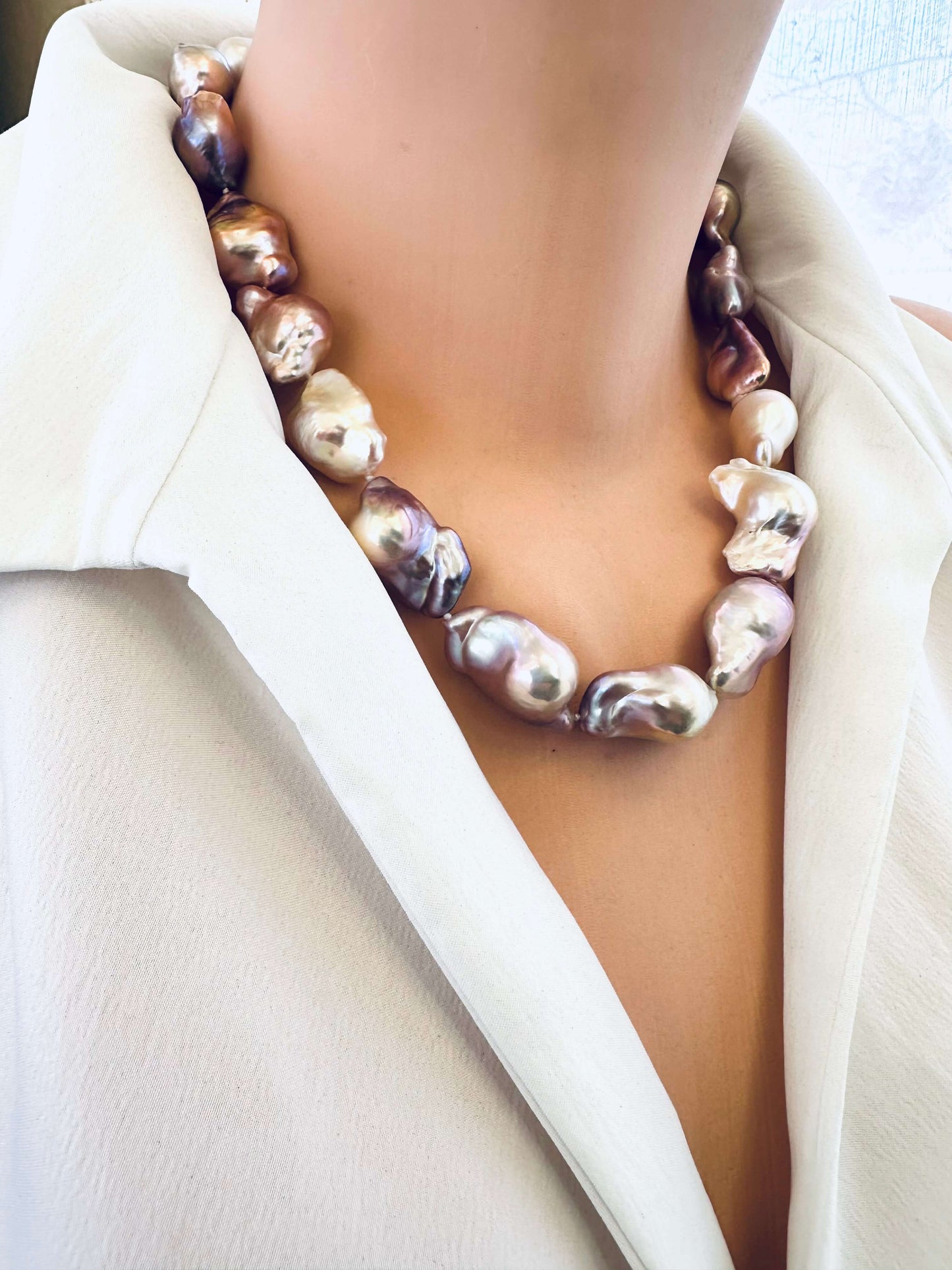 Pearl necklace worn by a person in a white blazer