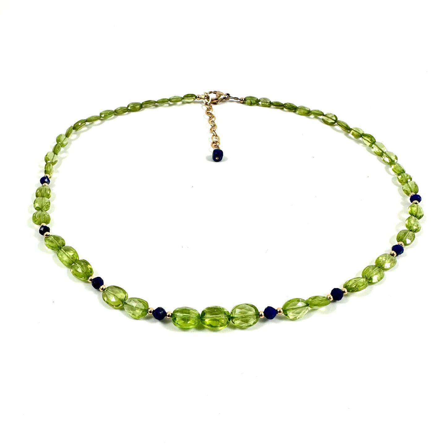 A beaded necklace featuring faceted light green beads, small dark blue beads, and a gold-tone clasp with a dangling blue bead, displayed on a clean white background.