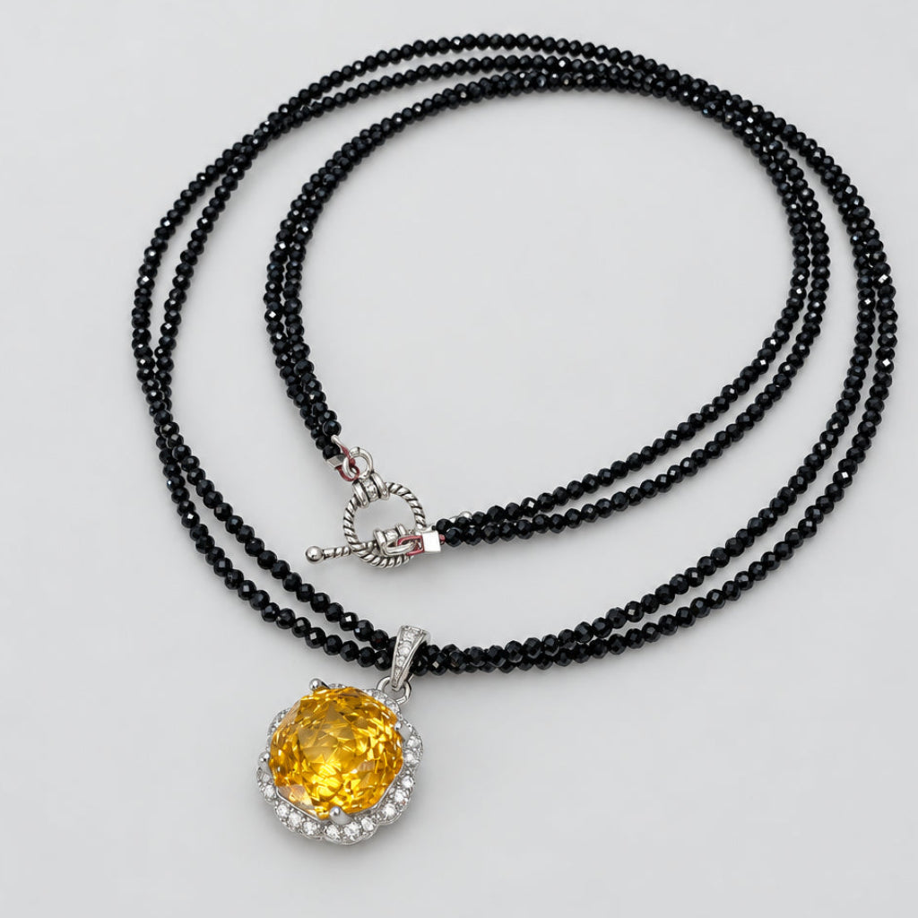 Black spinel and citrine pendant necklace on white background, handmade silver design