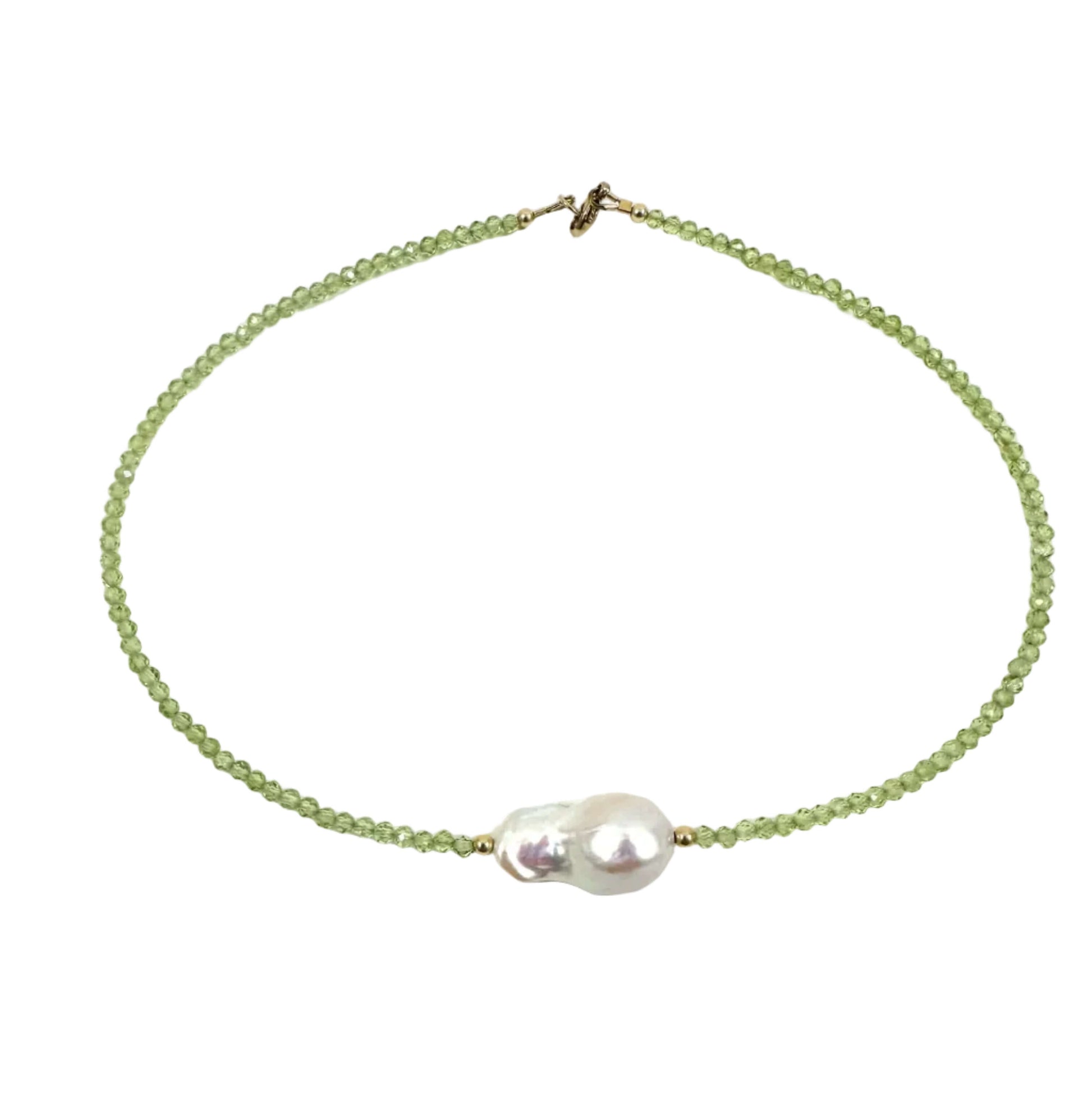 A delicate beaded necklace featuring light green faceted beads and a central cluster of a white baroque pearl, finished with a small gold clasp, shown on a plain white background.