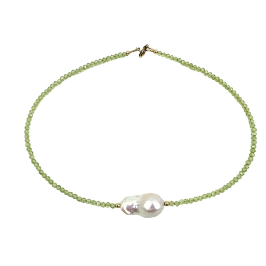 A delicate beaded necklace featuring light green faceted beads and a central cluster of a white baroque pearl, finished with a small gold clasp, shown on a plain white background.