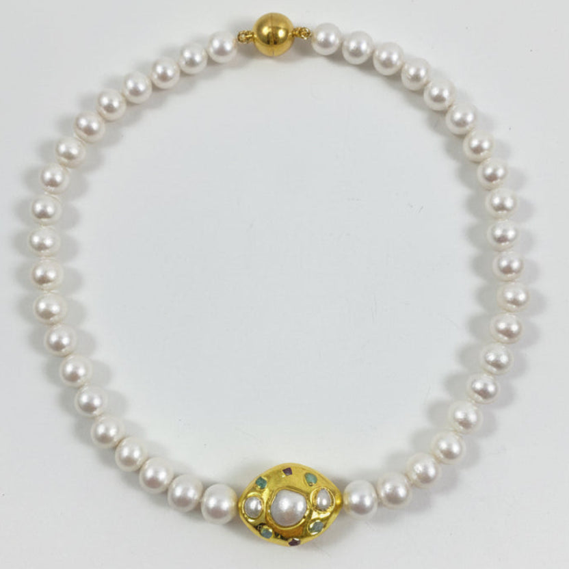 A pearl necklace with a gold-toned clasp featuring a central white pearl and small green and red accents, displayed on a plain white background.