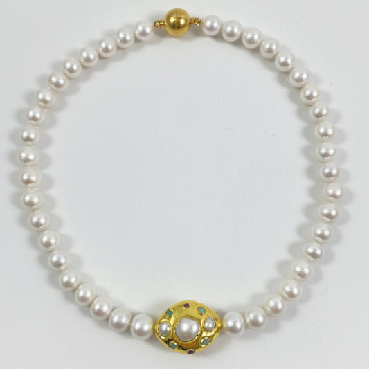 A pearl necklace with a gold-toned clasp featuring a central white pearl and small green and red accents, displayed on a plain white background.