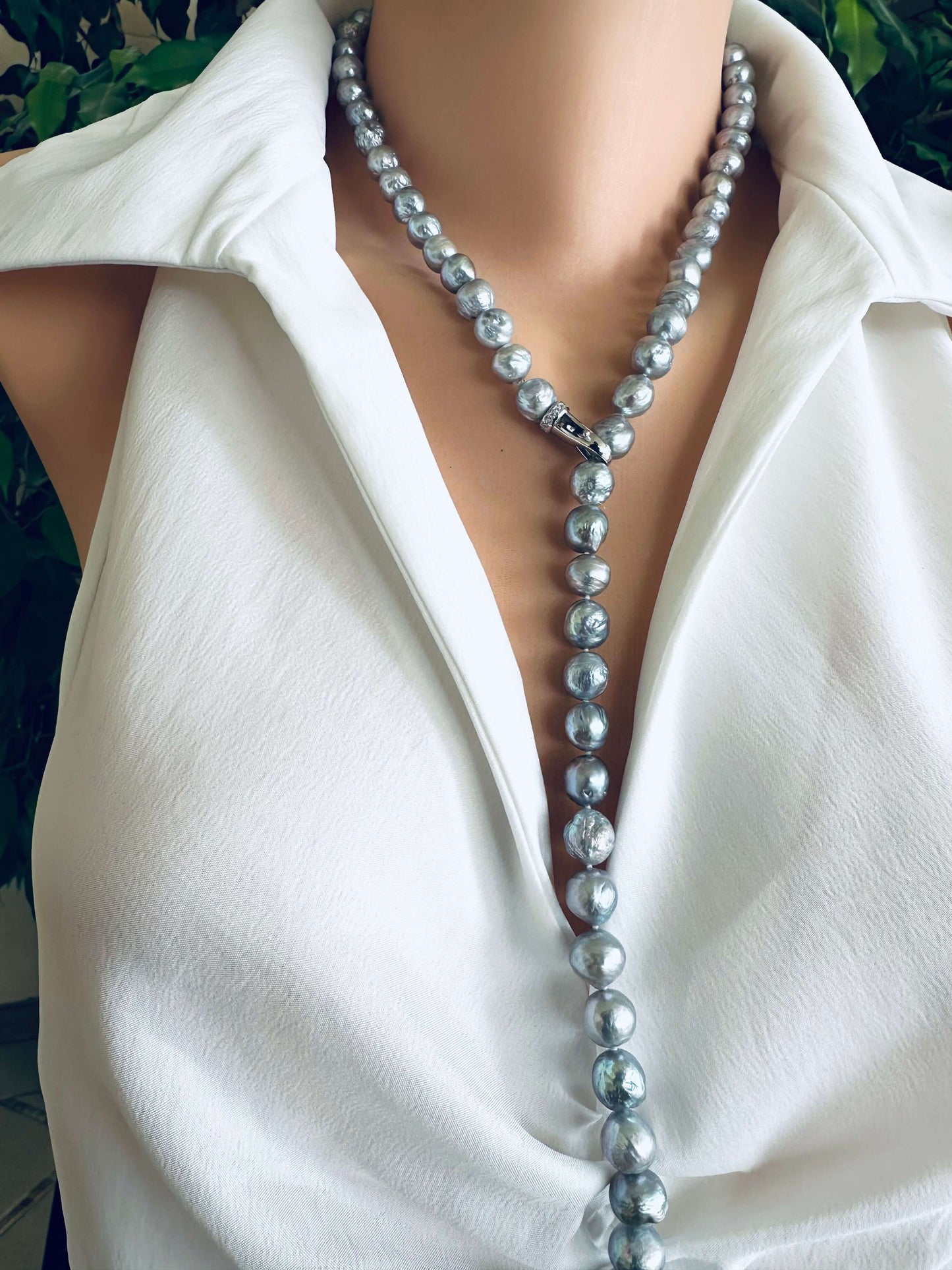 Pearl necklace worn by a person in a white shirt with a blurred background