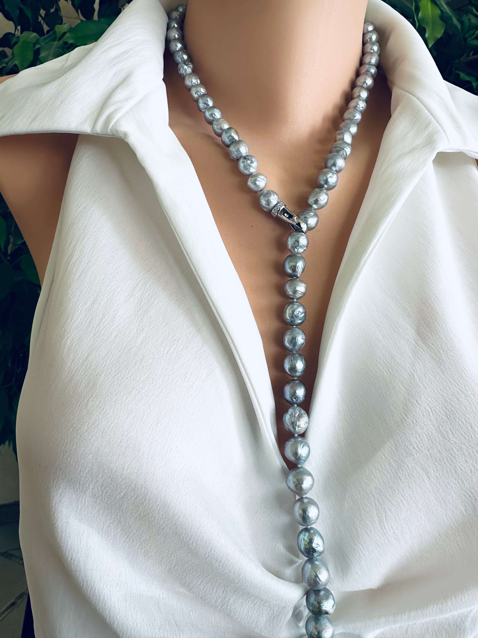 Pearl necklace worn by a person in a white shirt with a blurred background