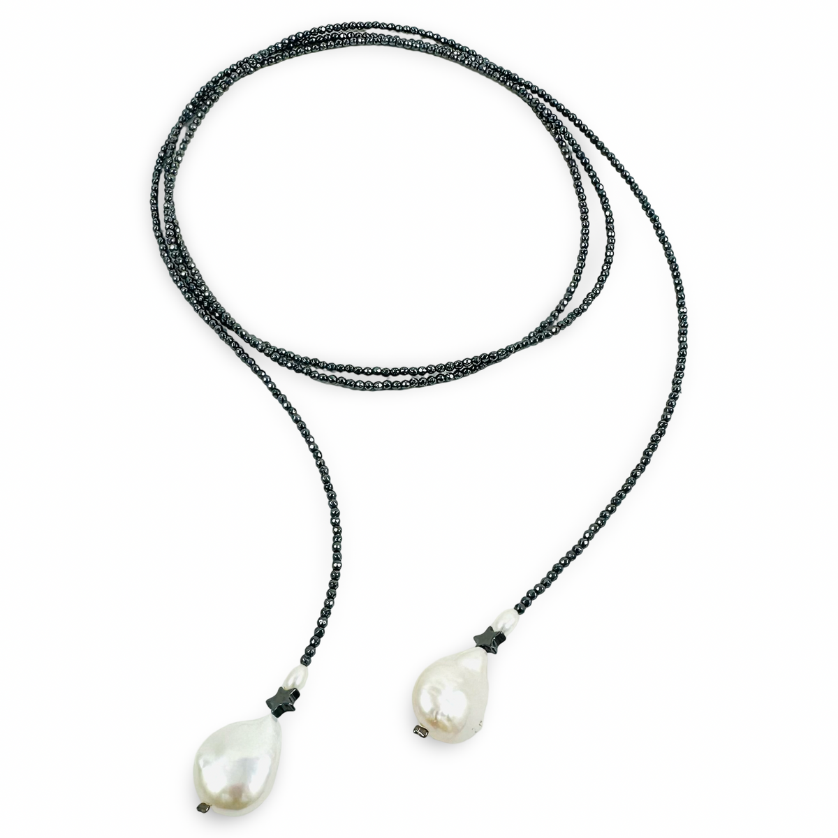 A long-strand beaded necklace with dark gray beads and two large, irregular white baroque pearls at the ends, displayed on a clean white background.
