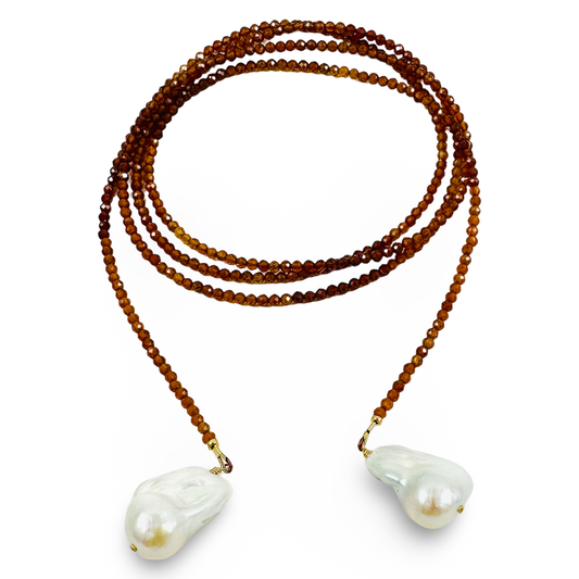 A beaded necklace featuring multiple strands of warm brown faceted beads leading to two large, irregular white baroque pearls, displayed on a clean white background.