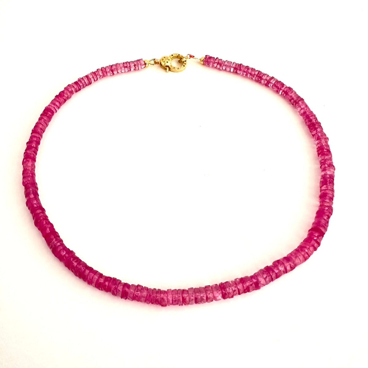 A beaded necklace made of small, faceted magenta-pink beads with a gold clasp, displayed on a plain white background.