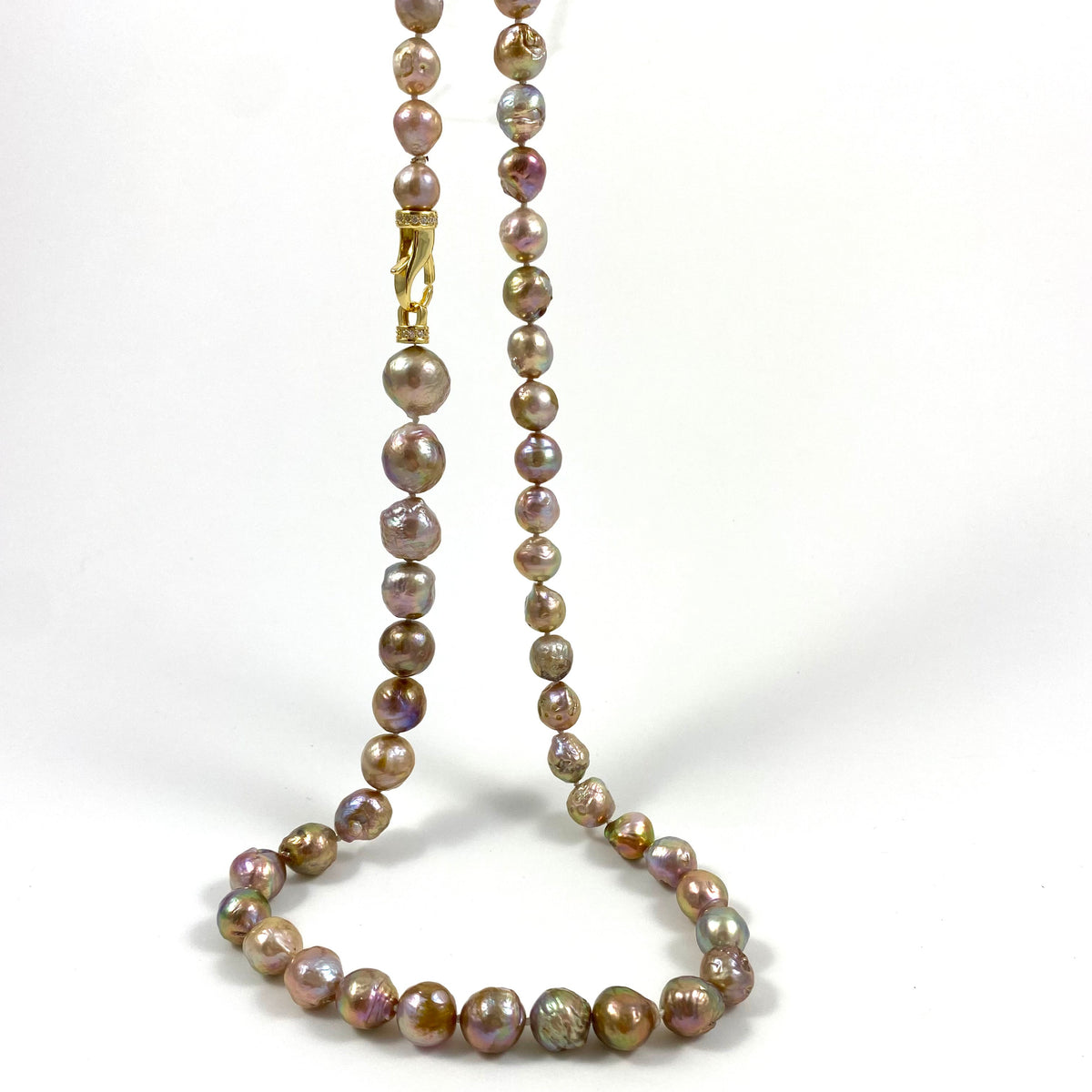 A strand of irregular baroque pearls in earthy brown, bronze, and muted purple tones, accented by a gold clasp, displayed on a clean white background.
