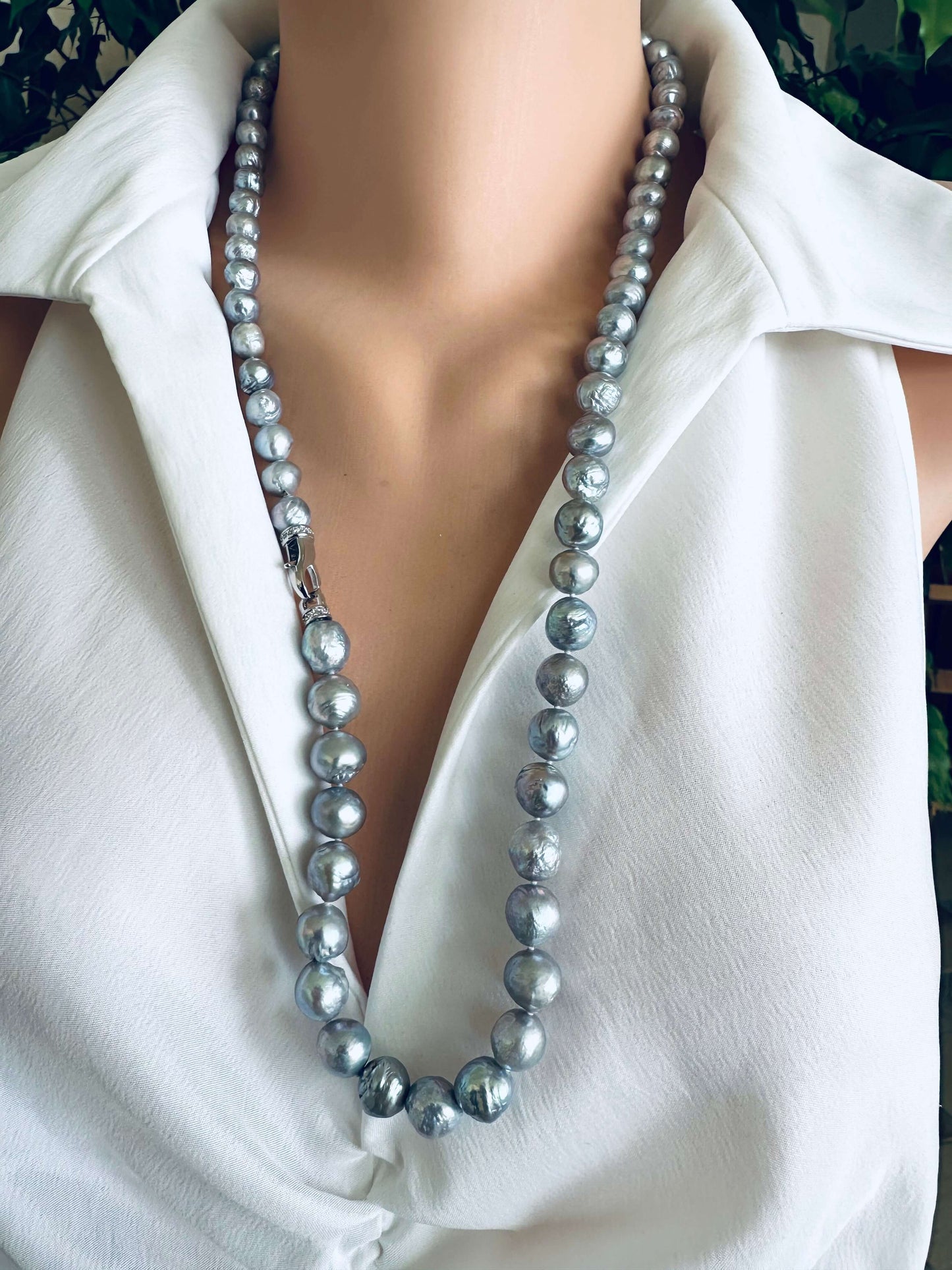 Pearl necklace worn by a person in a white shirt