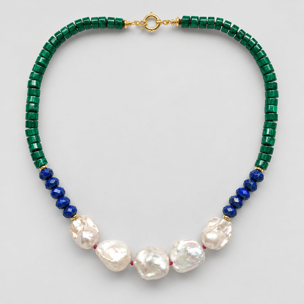 A beaded necklace featuring dark green faceted beads, a section of deep blue round beads, and five large white baroque pearls at the center, finished with a gold clasp, shown on a light gray background.
