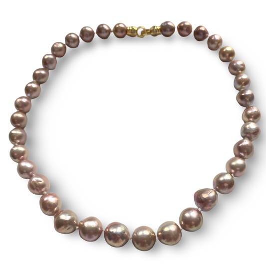A strand of irregular baroque pearls in a dusty mauve-purple hue with a gold clasp, displayed on a clean white background.
