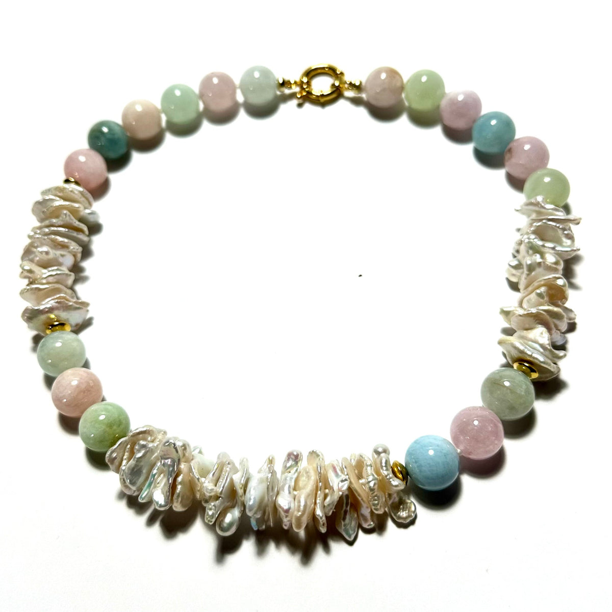 A beaded necklace featuring light pink, light green, and light blue round beads, accented by clusters of white mother-of-pearl chips and a gold clasp, displayed on a white background.