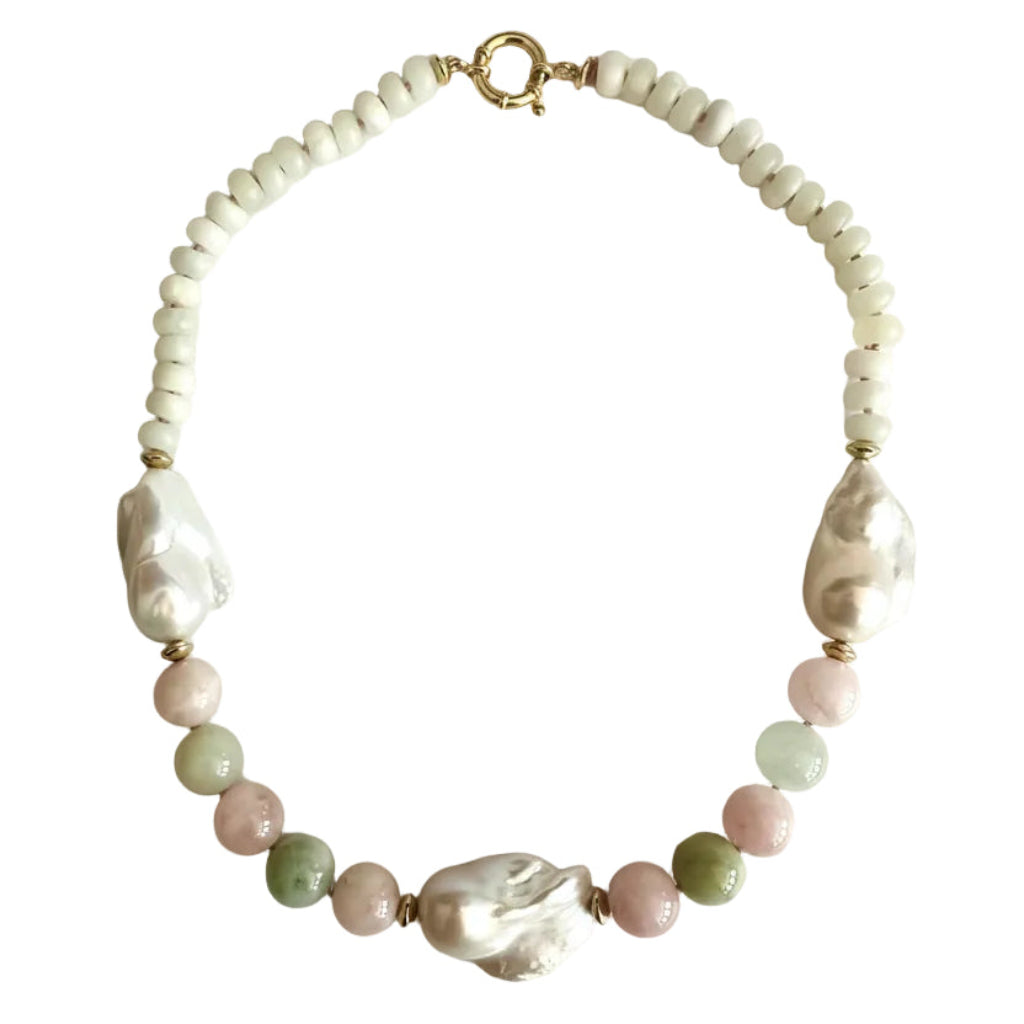A beaded necklace featuring white baroque pearls, pink and green round beads, and gold spacer beads, arranged in a circle on a light off-white background.