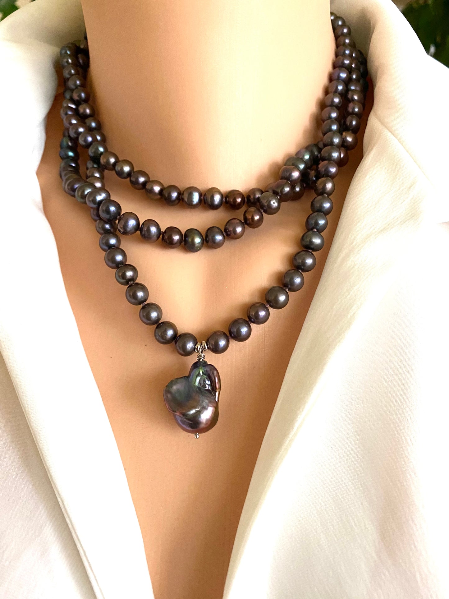 Pearl necklace with a heart-shaped pendant on a mannequin wearing a white blouse.