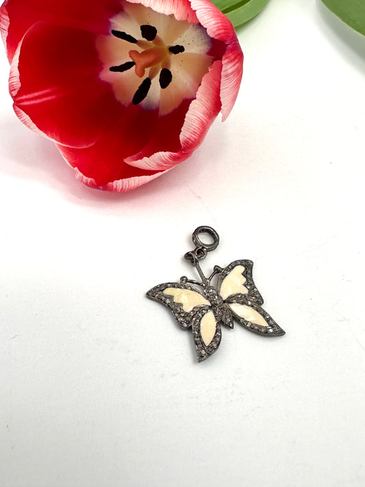 Butterfly pendant with white wings and black accents on a white background with a red tulip.